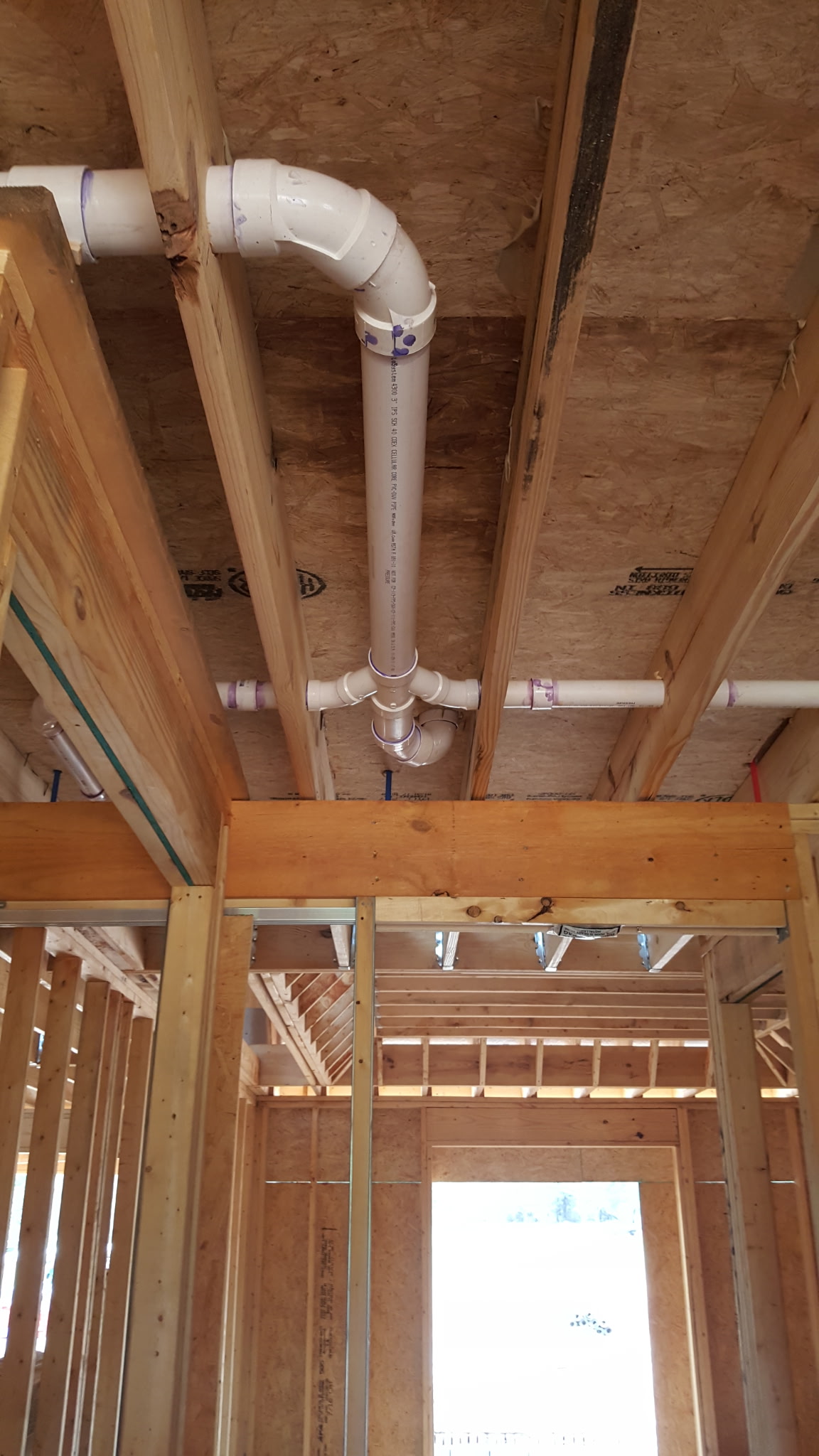 PVC drain and vent rough-in through floor joists in new construction