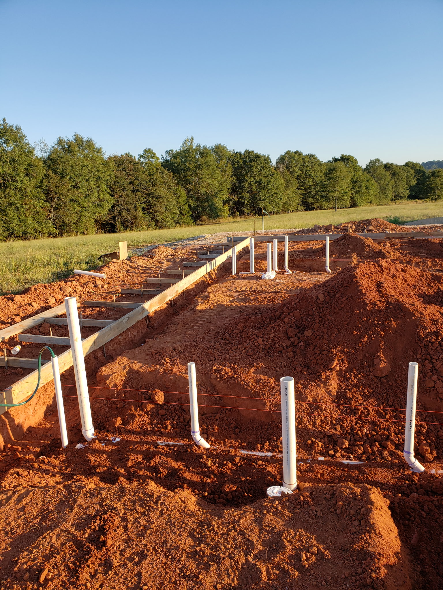 Underground PVC stub-outs set in red clay for a new foundation